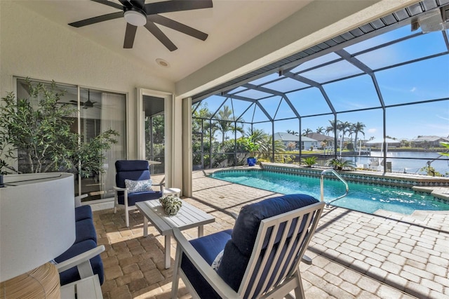 view of swimming pool featuring a water view, ceiling fan, a patio area, and glass enclosure