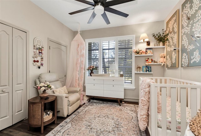 bedroom featuring hardwood / wood-style flooring, a nursery area, and ceiling fan