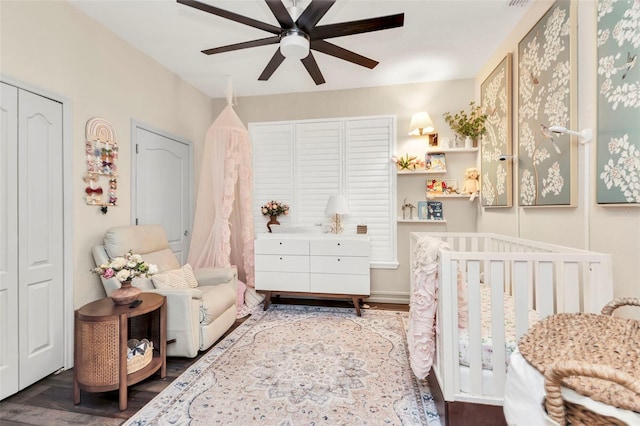 bedroom featuring a crib, hardwood / wood-style flooring, and ceiling fan