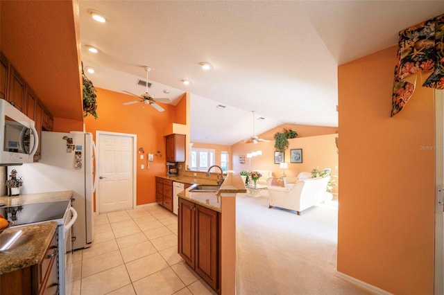 kitchen featuring light stone counters, white appliances, vaulted ceiling, and kitchen peninsula