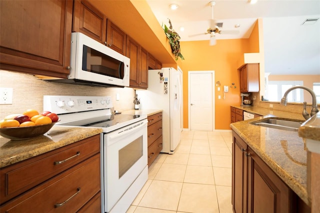 kitchen with sink, backsplash, light tile patterned floors, light stone counters, and white appliances