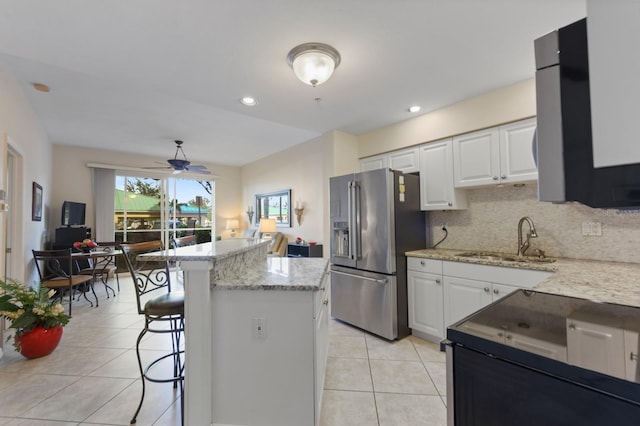 kitchen with high quality fridge, a breakfast bar, light stone countertops, and white cabinets