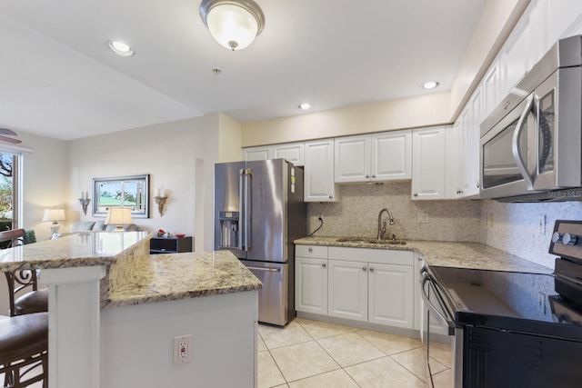 kitchen with sink, white cabinetry, stainless steel appliances, tasteful backsplash, and a kitchen bar