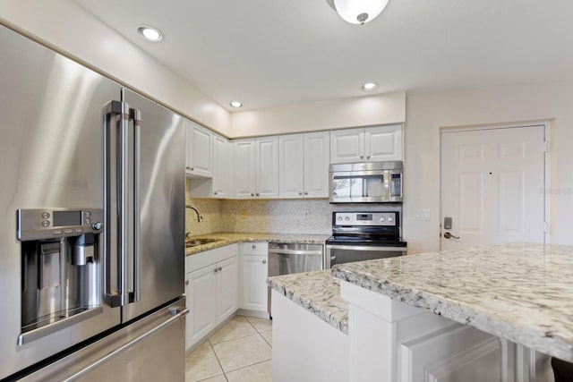 kitchen with white cabinetry, light stone countertops, stainless steel appliances, and sink