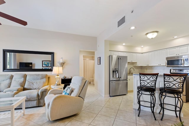 kitchen with light tile patterned floors, sink, appliances with stainless steel finishes, backsplash, and white cabinets