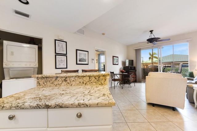 tiled living room with ceiling fan and stacked washer / dryer