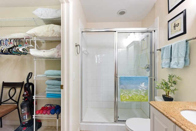 bathroom with tile patterned flooring, vanity, toilet, and walk in shower