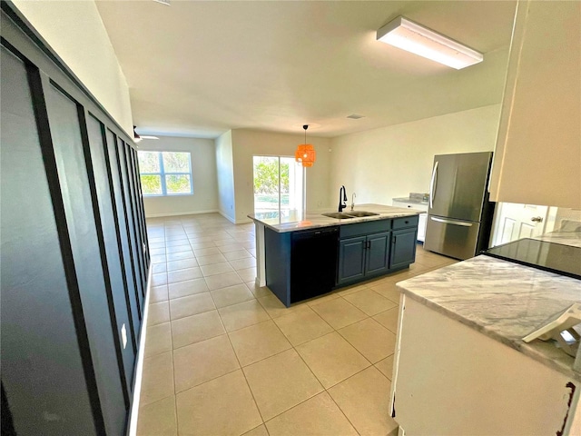 kitchen with sink, light tile patterned floors, stainless steel fridge, black dishwasher, and an island with sink