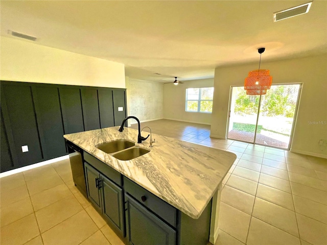 kitchen with sink, light tile patterned floors, ceiling fan, an island with sink, and decorative light fixtures