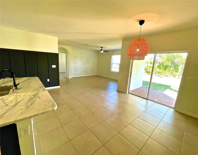 unfurnished dining area featuring light tile patterned floors, sink, and ceiling fan