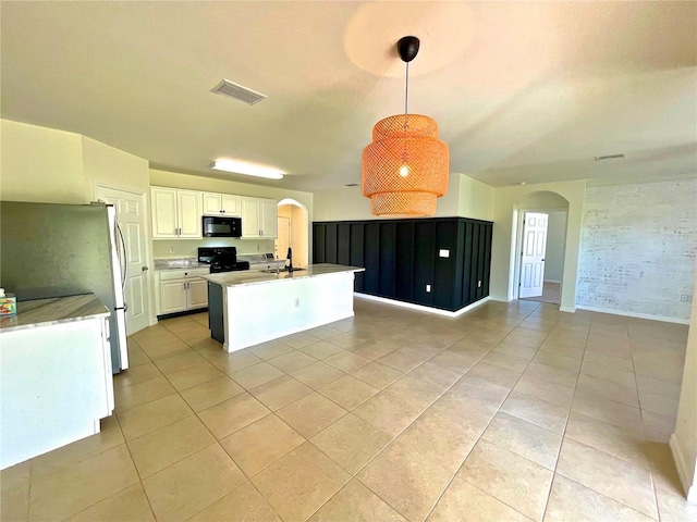 kitchen with decorative light fixtures, black appliances, a center island with sink, light tile patterned floors, and white cabinets