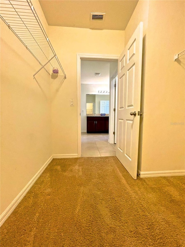 walk in closet with light carpet