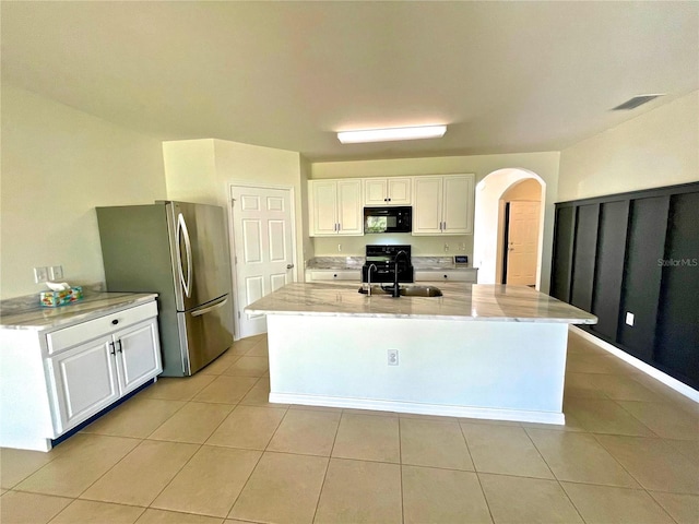 kitchen with white cabinetry, sink, stainless steel refrigerator, and an island with sink