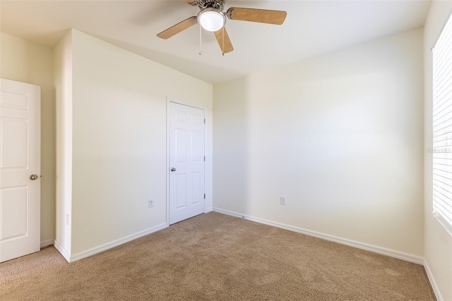 empty room featuring ceiling fan and light colored carpet