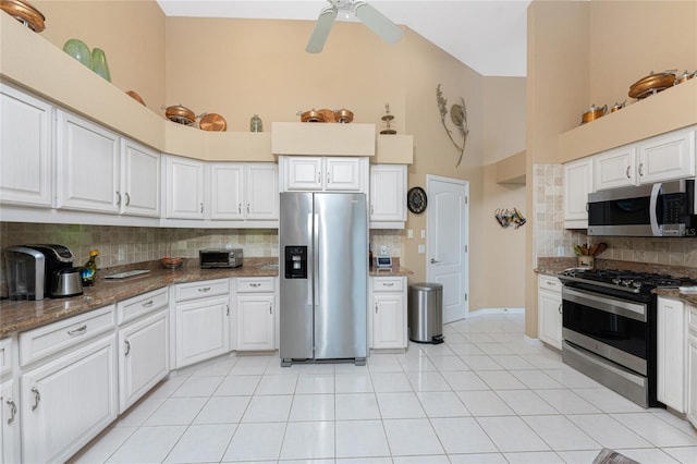 kitchen featuring high vaulted ceiling, appliances with stainless steel finishes, dark stone counters, decorative backsplash, and white cabinets