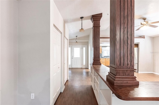 hall featuring lofted ceiling, dark wood-type flooring, and ornate columns