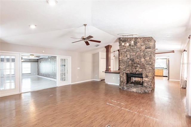 unfurnished living room with a stone fireplace, vaulted ceiling, ceiling fan, and hardwood / wood-style flooring