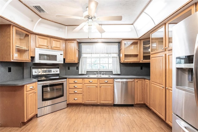 kitchen with sink, ceiling fan, appliances with stainless steel finishes, decorative backsplash, and light wood-type flooring