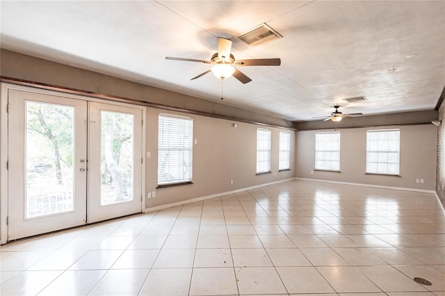 tiled spare room featuring ceiling fan and french doors