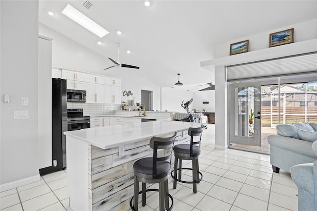 kitchen featuring light tile patterned floors, a breakfast bar, white cabinetry, range with electric cooktop, and kitchen peninsula