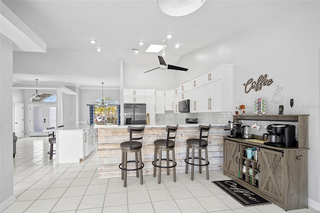 kitchen with a kitchen island, pendant lighting, a breakfast bar area, white cabinets, and stainless steel fridge