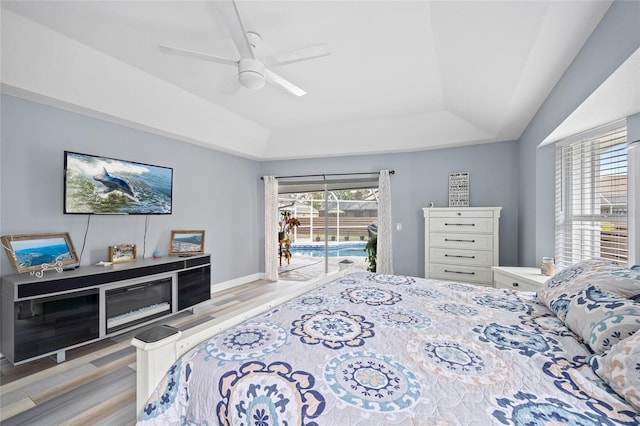 bedroom featuring ceiling fan, a raised ceiling, light wood-type flooring, and access to outside