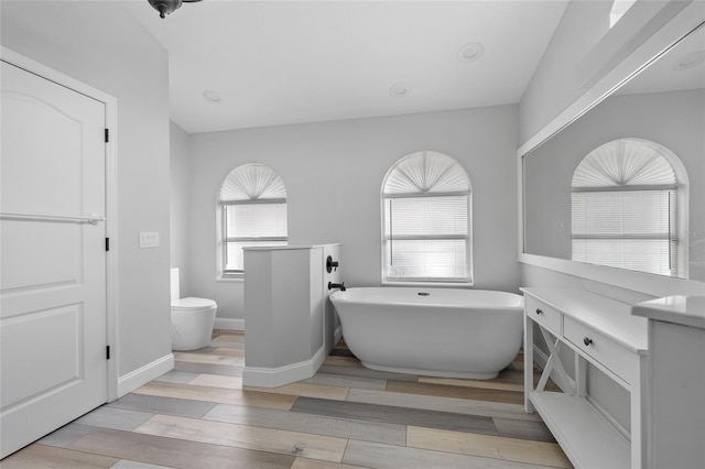 bathroom with vanity, a bathtub, toilet, and hardwood / wood-style flooring