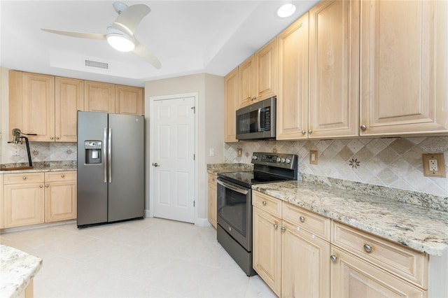 kitchen featuring stainless steel appliances, a raised ceiling, light tile patterned floors, and light brown cabinets