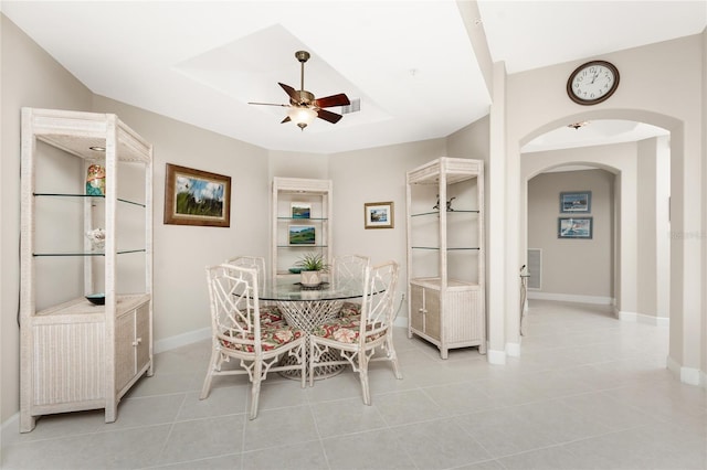 tiled dining area with a tray ceiling and ceiling fan