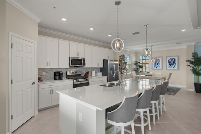 kitchen featuring a kitchen island with sink, sink, stainless steel appliances, and white cabinets