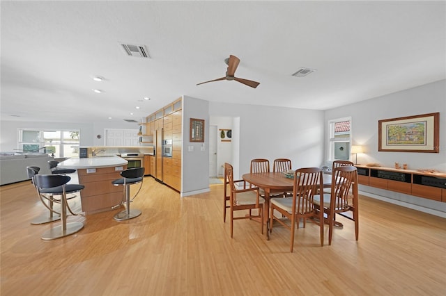 dining space featuring ceiling fan, sink, and light wood-type flooring