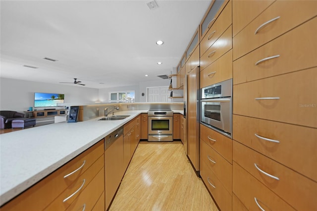 kitchen featuring stainless steel appliances, ceiling fan, sink, and light wood-type flooring