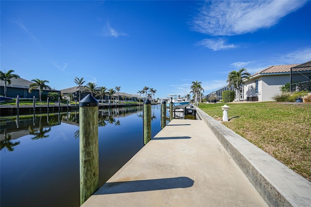 view of dock with a water view and a yard