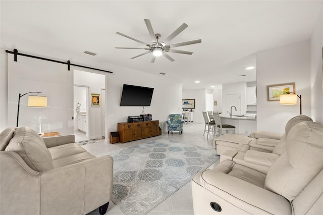 living room with ceiling fan, a barn door, and sink