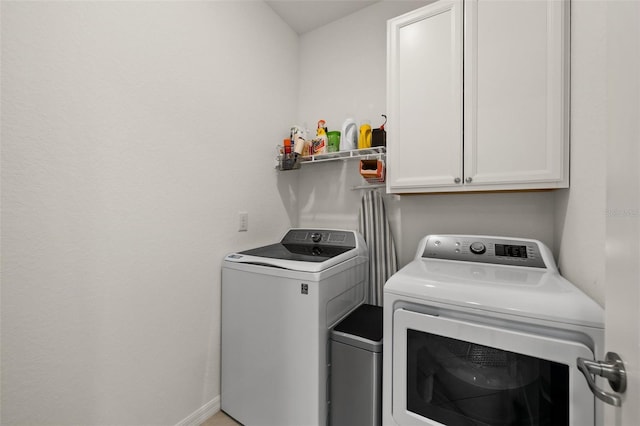 clothes washing area featuring cabinets and washer and dryer