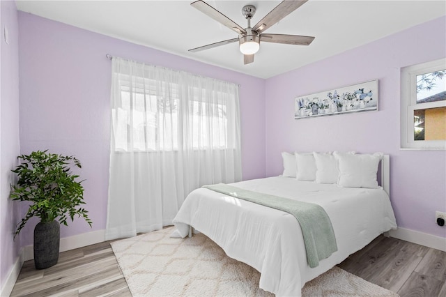 bedroom with multiple windows, light hardwood / wood-style floors, and ceiling fan