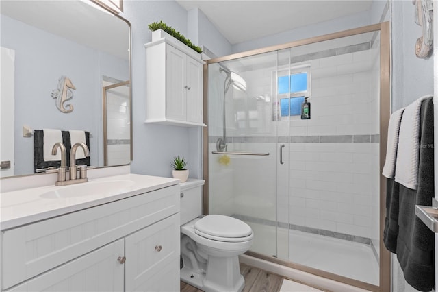 bathroom featuring vanity, toilet, an enclosed shower, and hardwood / wood-style floors