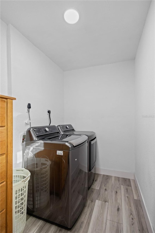 laundry area with washer and clothes dryer and light hardwood / wood-style floors