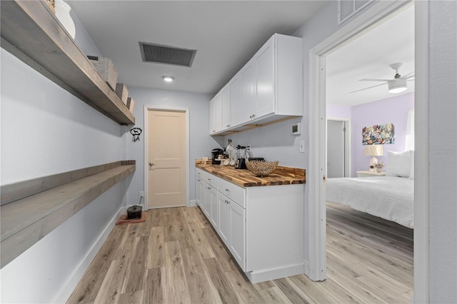 interior space with white cabinetry, wooden counters, ceiling fan, and light hardwood / wood-style flooring