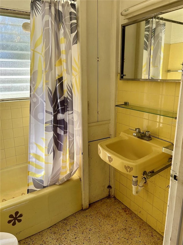 bathroom with sink, shower / bath combo with shower curtain, and decorative backsplash