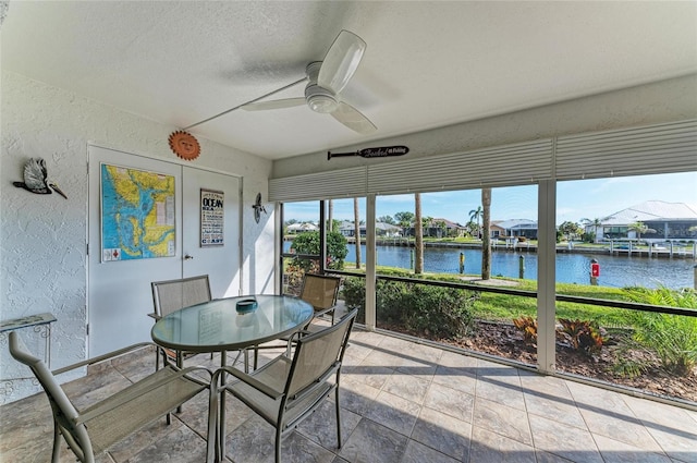 sunroom / solarium featuring a water view and ceiling fan