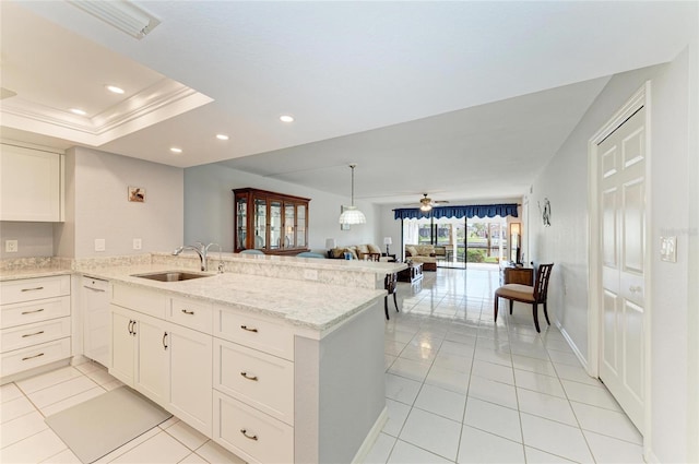 kitchen with kitchen peninsula, white cabinetry, sink, ceiling fan, and light stone counters