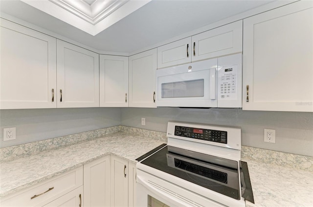 kitchen featuring light stone counters, white cabinets, and white appliances