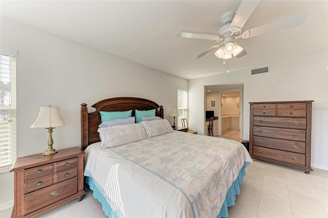 bedroom with light tile patterned flooring, ceiling fan, and ensuite bath