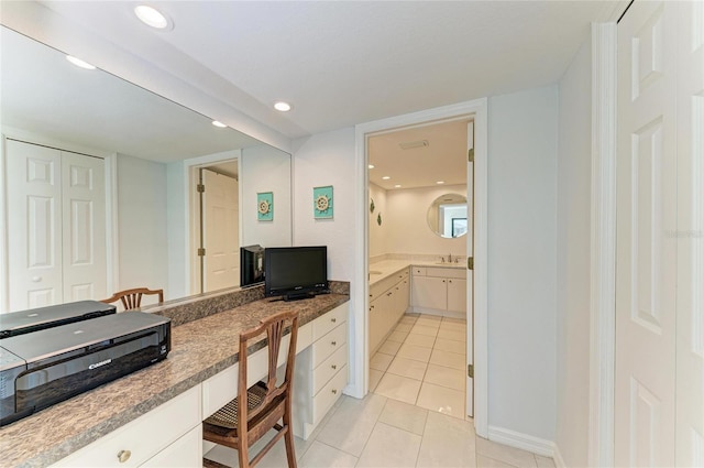 kitchen with white cabinetry, built in desk, and light tile patterned flooring