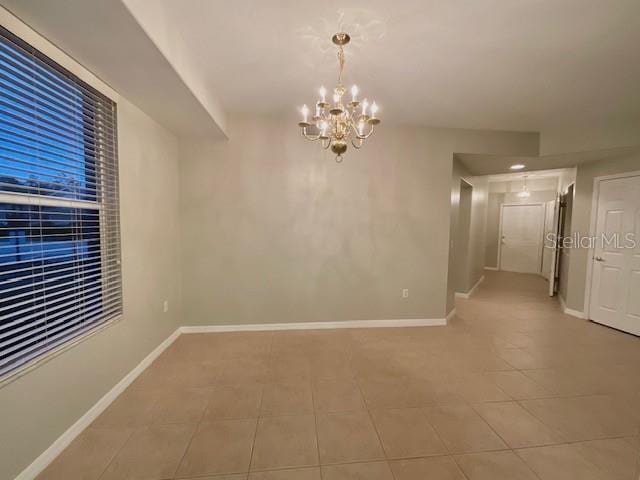 empty room with tile patterned flooring and an inviting chandelier