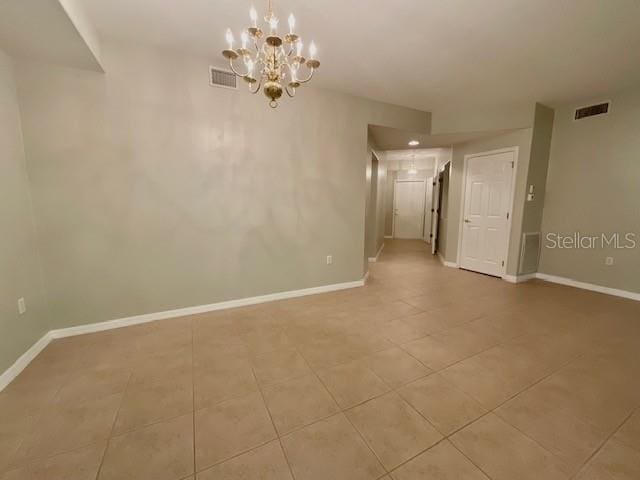 tiled empty room with a notable chandelier