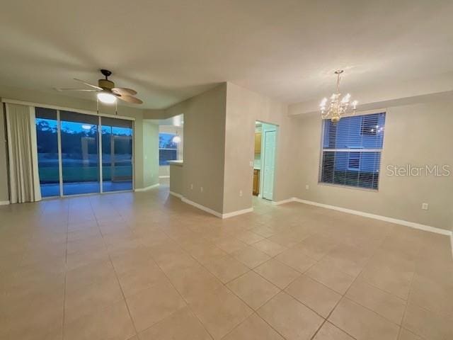 spare room featuring light tile patterned flooring and ceiling fan with notable chandelier