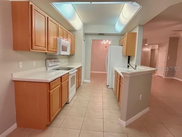 kitchen with light tile patterned flooring, sink, light brown cabinets, and white appliances