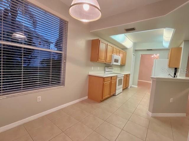 kitchen with light brown cabinetry, light tile patterned floors, and white appliances